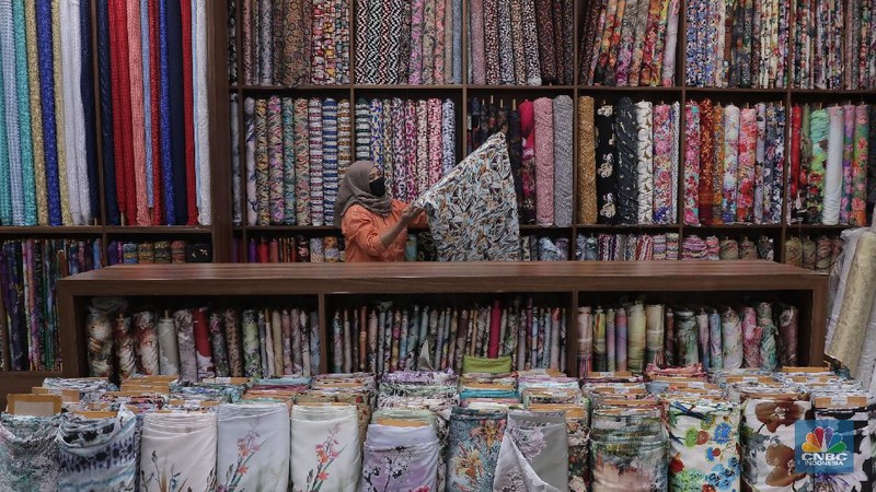 Pedagang beraktivitas di salah satu gerai kain di Pasar Mayestik, Jakarta, Rabu (11/11/2020). Pasar dalam negeri kembali dibanjiri oleh produk impor baik dalam bentuk kain maupun pakaian jadi di tengah lesunya industri domestik. Sengkarut industri tekstil terkait masalah impor masih belum berkesudahan. Saat ini ada tarik-tarikan kepentingan antara pelaku usaha industri soal mekanisme impor bahan baku yang efeknya bisa berbeda dari masing-masing industri hulu dan hilir. mengutip berita CNBC Indonesia pada 10 November, Kementerian Perdagangan dikabarkan bakal merevisi Peraturan Menteri Perdagangan (Permendag) mengenai aturan main importasi tekstil. Hal ini tidak lepas dari dorongan industri dalam negeri yang meminta adanya perubahan regulasi dari aturan-aturan yang lama. Maklum, beberapa revisi Permendag yang mengatur impor sejak tahun 2015 dinilai selalu pro barang impor. Pantauan CNBC Indonesia salah satu pemilik toko mengatakan bahwa bahan yang ia beli Grosiran di Bandung, Tasik dan sekitarnya. Namun tidak diketahui dari Mama bahan dasar tekstil itu berasal. Kalangan industri tekstil dan produk tekstil (TPT) termasuk di sektor hulu seperti benang masih mengeluhkan adanya gangguan produk impor. Masih ada persoalan tak harmoninya kebijakan sehingga ada industri yang kena dampak.  (CNBC Indonesia/Muhammad Sabki)