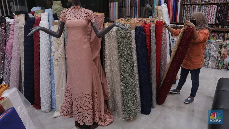 Pedagang beraktivitas di salah satu gerai kain di Pasar Mayestik, Jakarta, Rabu (11/11/2020). Pasar dalam negeri kembali dibanjiri oleh produk impor baik dalam bentuk kain maupun pakaian jadi di tengah lesunya industri domestik. Sengkarut industri tekstil terkait masalah impor masih belum berkesudahan. Saat ini ada tarik-tarikan kepentingan antara pelaku usaha industri soal mekanisme impor bahan baku yang efeknya bisa berbeda dari masing-masing industri hulu dan hilir. mengutip berita CNBC Indonesia pada 10 November, Kementerian Perdagangan dikabarkan bakal merevisi Peraturan Menteri Perdagangan (Permendag) mengenai aturan main importasi tekstil. Hal ini tidak lepas dari dorongan industri dalam negeri yang meminta adanya perubahan regulasi dari aturan-aturan yang lama. Maklum, beberapa revisi Permendag yang mengatur impor sejak tahun 2015 dinilai selalu pro barang impor. Pantauan CNBC Indonesia salah satu pemilik toko mengatakan bahwa bahan yang ia beli Grosiran di Bandung, Tasik dan sekitarnya. Namun tidak diketahui dari Mama bahan dasar tekstil itu berasal. Kalangan industri tekstil dan produk tekstil (TPT) termasuk di sektor hulu seperti benang masih mengeluhkan adanya gangguan produk impor. Masih ada persoalan tak harmoninya kebijakan sehingga ada industri yang kena dampak. (CNBC Indonesia/Muhammad Sabki)