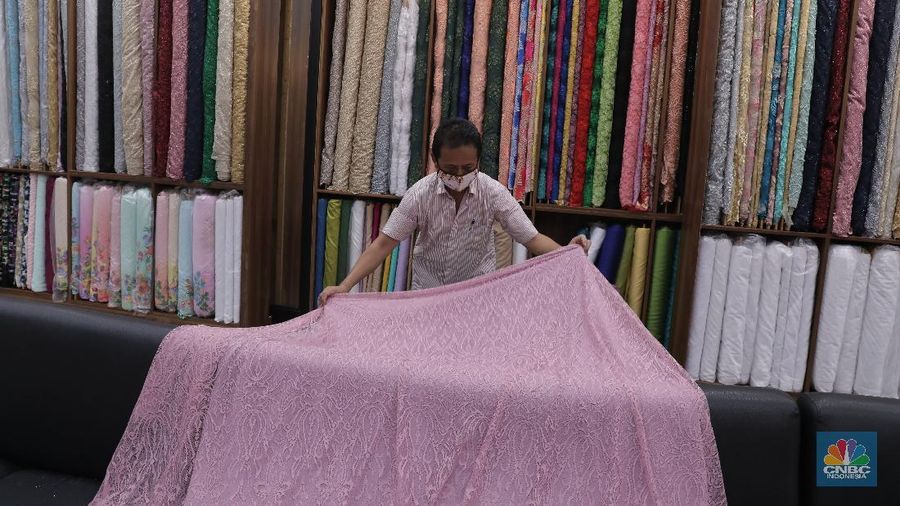 Pedagang beraktivitas di salah satu gerai kain di Pasar Mayestik, Jakarta, Rabu (11/11/2020). Pasar dalam negeri kembali dibanjiri oleh produk impor baik dalam bentuk kain maupun pakaian jadi di tengah lesunya industri domestik. Sengkarut industri tekstil terkait masalah impor masih belum berkesudahan. Saat ini ada tarik-tarikan kepentingan antara pelaku usaha industri soal mekanisme impor bahan baku yang efeknya bisa berbeda dari masing-masing industri hulu dan hilir. mengutip berita CNBC Indonesia pada 10 November, Kementerian Perdagangan dikabarkan bakal merevisi Peraturan Menteri Perdagangan (Permendag) mengenai aturan main importasi tekstil. Hal ini tidak lepas dari dorongan industri dalam negeri yang meminta adanya perubahan regulasi dari aturan-aturan yang lama. Maklum, beberapa revisi Permendag yang mengatur impor sejak tahun 2015 dinilai selalu pro barang impor. Pantauan CNBC Indonesia salah satu pemilik toko mengatakan bahwa bahan yang ia beli Grosiran di Bandung, Tasik dan sekitarnya. Namun tidak diketahui dari Mama bahan dasar tekstil itu berasal. Kalangan industri tekstil dan produk tekstil (TPT) termasuk di sektor hulu seperti benang masih mengeluhkan adanya gangguan produk impor. Masih ada persoalan tak harmoninya kebijakan sehingga ada industri yang kena dampak.  (CNBC Indonesia/Muhammad Sabki)