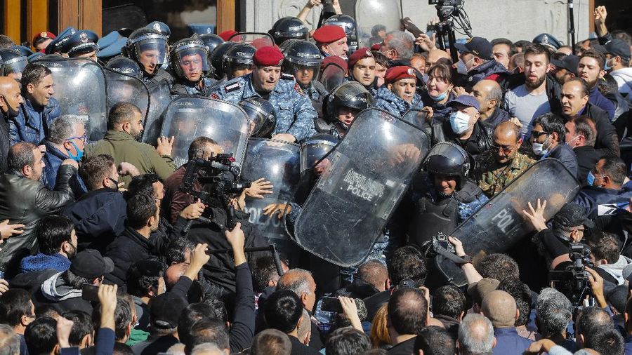 Protesters gather near the parliamentary building during a protest against an agreement to halt fighting over the Nagorno-Karabakh region, in Yerevan, Armenia, Wednesday, Nov. 11, 2020. Thousands of people flooded the streets of Yerevan once again on Wednesday, protesting an agreement between Armenia and Azerbaijan to halt the fighting over Nagorno-Karabakh, which calls for deployment of nearly 2,000 Russian peacekeepers and territorial concessions. Protesters clashed with police, and scores have been detained. (AP Photo/Dmitri Lovetsky)