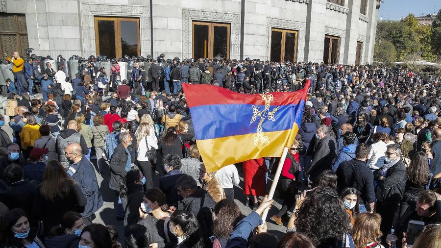Protesters gather near the parliamentary building during a protest against an agreement to halt fighting over the Nagorno-Karabakh region, in Yerevan, Armenia, Wednesday, Nov. 11, 2020. Thousands of people flooded the streets of Yerevan once again on Wednesday, protesting an agreement between Armenia and Azerbaijan to halt the fighting over Nagorno-Karabakh, which calls for deployment of nearly 2,000 Russian peacekeepers and territorial concessions. Protesters clashed with police, and scores have been detained. (AP Photo/Dmitri Lovetsky)