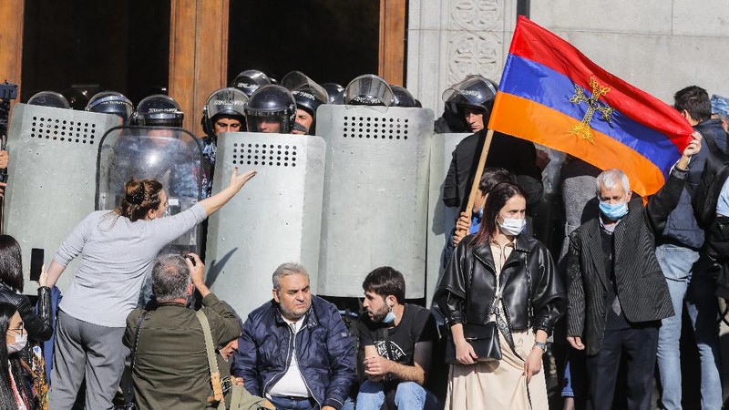 Protesters gather near the parliamentary building during a protest against an agreement to halt fighting over the Nagorno-Karabakh region, in Yerevan, Armenia, Wednesday, Nov. 11, 2020. Thousands of people flooded the streets of Yerevan once again on Wednesday, protesting an agreement between Armenia and Azerbaijan to halt the fighting over Nagorno-Karabakh, which calls for deployment of nearly 2,000 Russian peacekeepers and territorial concessions. Protesters clashed with police, and scores have been detained. (AP Photo/Dmitri Lovetsky)