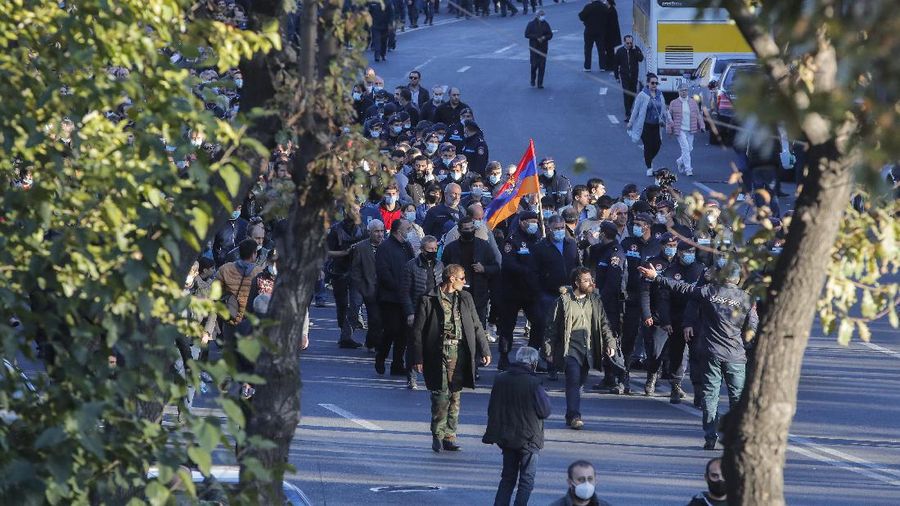 Protesters gather near the parliamentary building during a protest against an agreement to halt fighting over the Nagorno-Karabakh region, in Yerevan, Armenia, Wednesday, Nov. 11, 2020. Thousands of people flooded the streets of Yerevan once again on Wednesday, protesting an agreement between Armenia and Azerbaijan to halt the fighting over Nagorno-Karabakh, which calls for deployment of nearly 2,000 Russian peacekeepers and territorial concessions. Protesters clashed with police, and scores have been detained. (AP Photo/Dmitri Lovetsky)