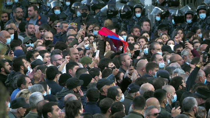 Demo Warga Armenia terhadap gencatna Senjata Protesters gather near the parliamentary building during a protest against an agreement to halt fighting over the Nagorno-Karabakh region, in Yerevan, Armenia, Wednesday, Nov. 11, 2020. Thousands of people flooded the streets of Yerevan once again on Wednesday, protesting an agreement between Armenia and Azerbaijan to halt the fighting over Nagorno-Karabakh, which calls for deployment of nearly 2,000 Russian peacekeepers and territorial concessions. Protesters clashed with police, and scores have been detained. (AP Photo/Dmitri Lovetsky)