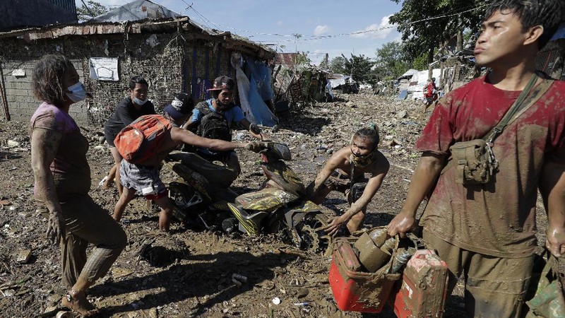 \Warga menyelamatkan barang berharga yang masih bisa digunakan saat terkena banjir akibat terjangan Topan Vamco di Filipina. (AP/Aaron Favila)