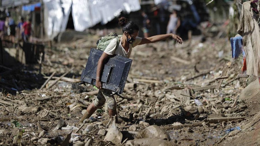 \Warga menyelamatkan barang berharga yang masih bisa digunakan saat terkena banjir akibat terjangan Topan Vamco di Filipina. (AP/Aaron Favila)