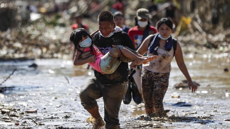 \Warga menyelamatkan barang berharga yang masih bisa digunakan saat terkena banjir akibat terjangan Topan Vamco di Filipina. (AP/Aaron Favila)