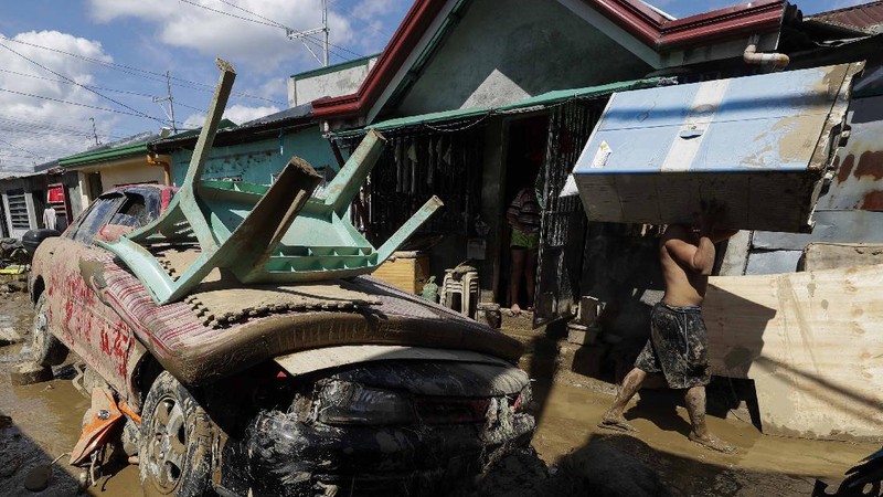 \Warga menyelamatkan barang berharga yang masih bisa digunakan saat terkena banjir akibat terjangan Topan Vamco di Filipina. (AP/Aaron Favila)