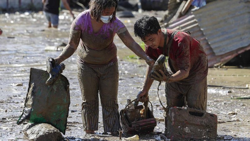\Warga menyelamatkan barang berharga yang masih bisa digunakan saat terkena banjir akibat terjangan Topan Vamco di Filipina. (AP/Aaron Favila)