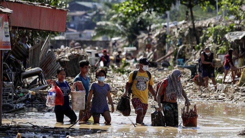 \Warga menyelamatkan barang berharga yang masih bisa digunakan saat terkena banjir akibat terjangan Topan Vamco di Filipina. (AP/Aaron Favila)