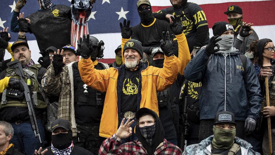 A person in a President Donald Trump mask poses for photos in front of a background with Trump on it as supporters attend pro-Trump marches, Saturday Nov. 14, 2020, in Washington. (AP Photo/Jacquelyn Martin)
