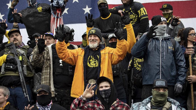 A person in a President Donald Trump mask poses for photos in front of a background with Trump on it as supporters attend pro-Trump marches, Saturday Nov. 14, 2020, in Washington. (AP Photo/Jacquelyn Martin)