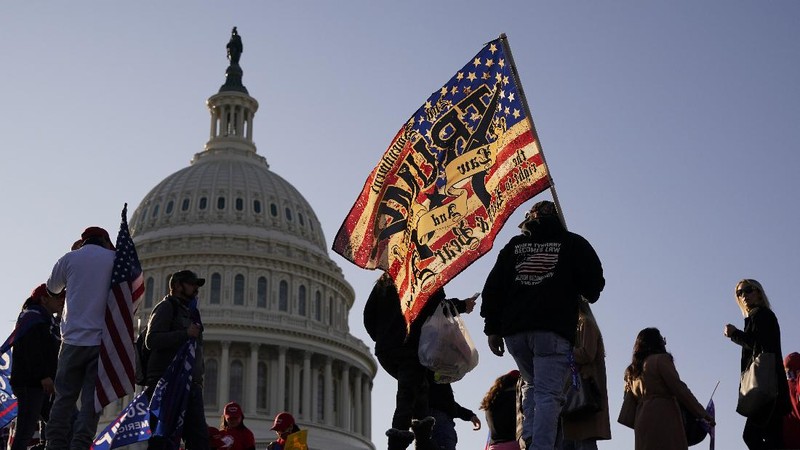 A person in a President Donald Trump mask poses for photos in front of a background with Trump on it as supporters attend pro-Trump marches, Saturday Nov. 14, 2020, in Washington. (AP Photo/Jacquelyn Martin)