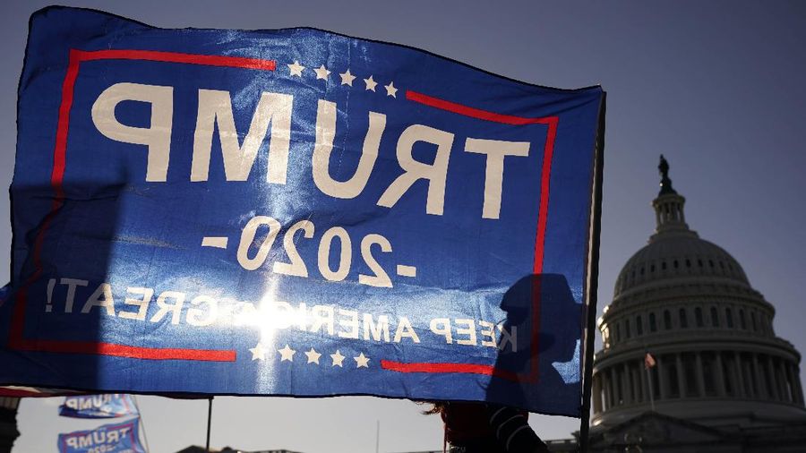 A supporter of President Donald Trump holds a Trump 2020 flag outside the U.S. Capitol building as they attend pro-Trump marches, Saturday Nov. 14, 2020, in Washington. (AP Photo/Jacquelyn Martin)