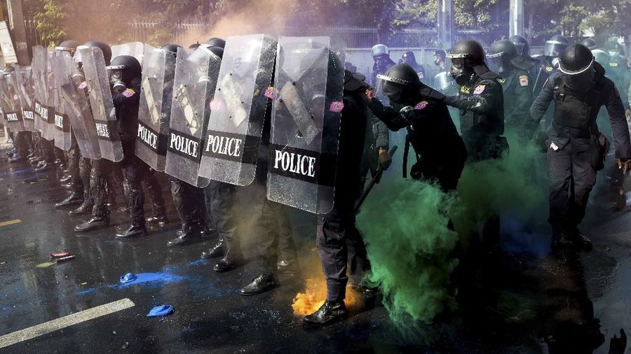 Polisi Thailand menembakan gas air mata kepada para demonstran yang mulai menembus barikade keamanan di depan kantor parlemen Thailand. (AP/Sakchai Lalit)