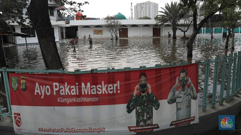 Warga melintasi genangan air rob di kawasan Pelabuhan Perikanan Muara Baru, Jakarta Utara, Selasa, (17/11/2020). (CNBC Indonesia/Muhammad Sabki)