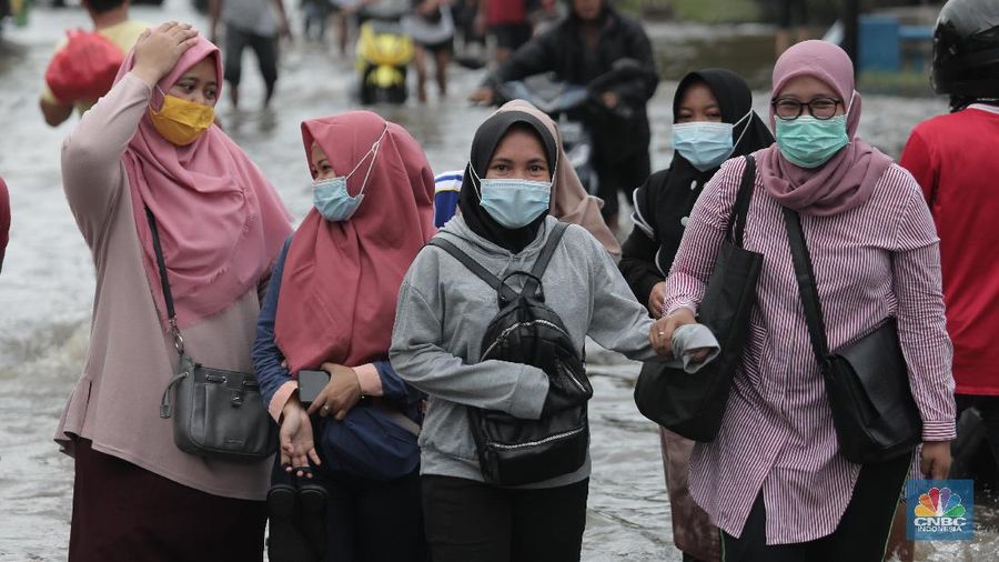 Warga melintasi genangan air rob di kawasan Pelabuhan Perikanan Muara Baru, Jakarta Utara, Selasa, (17/11/2020). (CNBC Indonesia/Muhammad Sabki)