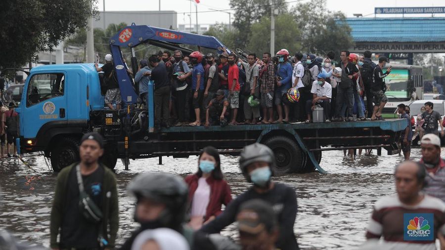 Warga melintasi genangan air rob di kawasan Pelabuhan Perikanan Muara Baru, Jakarta Utara, Selasa, (17/11/2020). (CNBC Indonesia/Muhammad Sabki)