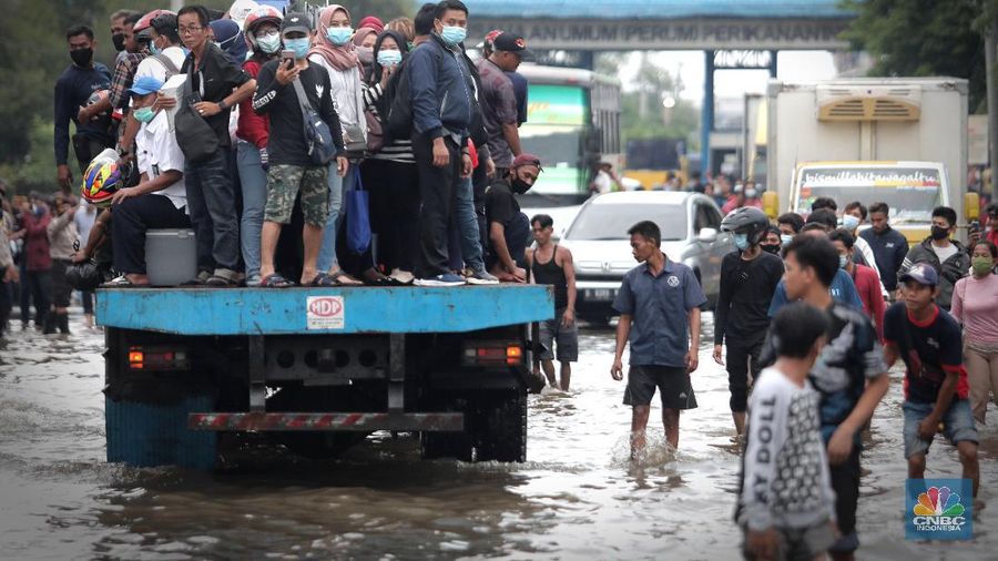 Warga melintasi genangan air rob di kawasan Pelabuhan Perikanan Muara Baru, Jakarta Utara, Selasa, (17/11/2020). (CNBC Indonesia/Muhammad Sabki)