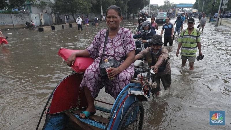 Warga melintasi genangan air rob di kawasan Pelabuhan Perikanan Muara Baru, Jakarta Utara, Selasa, (17/11/2020). (CNBC Indonesia/Muhammad Sabki)