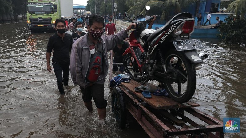 Warga melintasi genangan air rob di kawasan Pelabuhan Perikanan Muara Baru, Jakarta Utara, Selasa, (17/11/2020). (CNBC Indonesia/Muhammad Sabki)