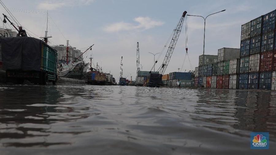 Warga melintasi genangan air rob di kawasan Pelabuhan Perikanan Muara Baru, Jakarta Utara, Selasa, (17/11/2020). (CNBC Indonesia/Muhammad Sabki)