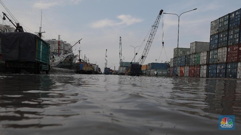 Warga melintasi genangan air rob di kawasan Pelabuhan Perikanan Muara Baru, Jakarta Utara, Selasa, (17/11/2020). (CNBC Indonesia/Muhammad Sabki)