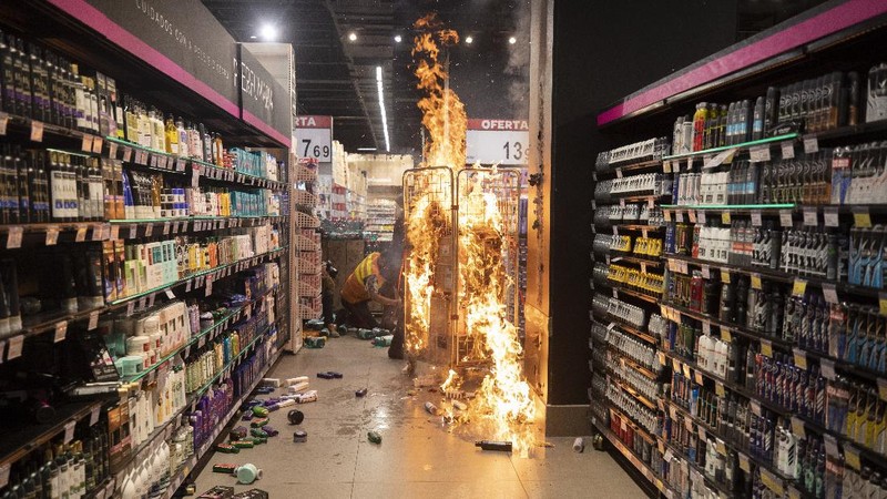 Demonstrators use a crowd control barrier to smash into the entrance of a Carrefour supermarket during a protest against the murder of Black man Joao Alberto Silveira Freitas at a different Carrefour supermarket the night before, on Brazil's National Black Consciousness Day in Rio de Janeiro, Brazil, Friday, Nov. 20, 2020. Freitas died after being beaten by supermarket security guards in the southern Brazilian city of Porto Alegre, sparking outrage as videos of the incident circulated on social media.  (AP Photo/Andre Penner)