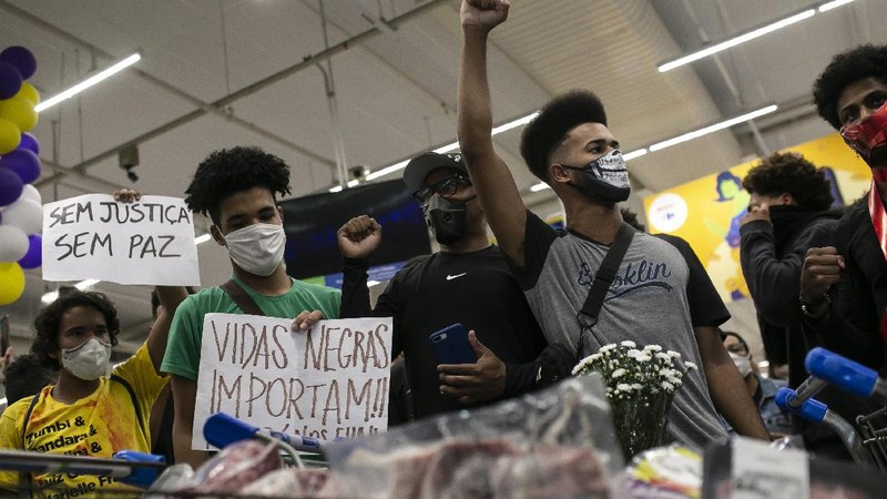 Demonstrators use a crowd control barrier to smash into the entrance of a Carrefour supermarket during a protest against the murder of Black man Joao Alberto Silveira Freitas at a different Carrefour supermarket the night before, on Brazil's National Black Consciousness Day in Rio de Janeiro, Brazil, Friday, Nov. 20, 2020. Freitas died after being beaten by supermarket security guards in the southern Brazilian city of Porto Alegre, sparking outrage as videos of the incident circulated on social media.  (AP Photo/Andre Penner)