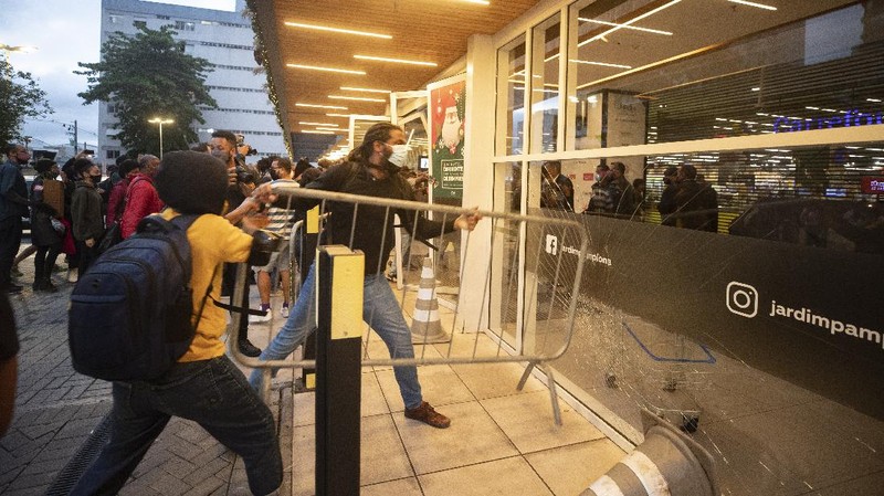 Demonstrators use a crowd control barrier to smash into the entrance of a Carrefour supermarket during a protest against the murder of Black man Joao Alberto Silveira Freitas at a different Carrefour supermarket the night before, on Brazil's National Black Consciousness Day in Rio de Janeiro, Brazil, Friday, Nov. 20, 2020. Freitas died after being beaten by supermarket security guards in the southern Brazilian city of Porto Alegre, sparking outrage as videos of the incident circulated on social media.  (AP Photo/Andre Penner)