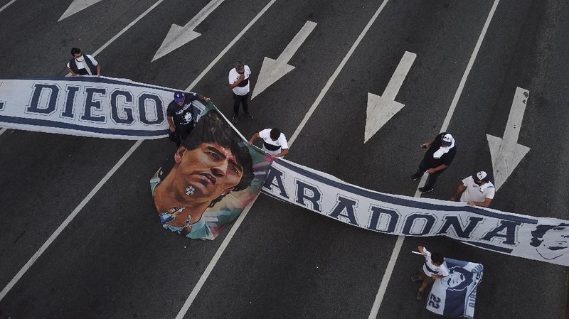 Soccer fans carry a banner of Diego Maradona in downtown Buenos Aires, Argentina, Wednesday, Nov. 25, 2020. Diego Maradona, the Argentine soccer great who was among the best players ever and who led his country to the 1986 World Cup title died from a heart attack at his home in Buenos Aires. He was 60. (AP Photo/Victor Caivano)
