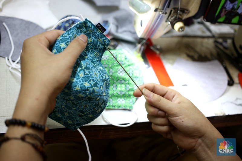 Perajin memproduksi masker batik di Sentra Kerajinan Batik Tradisiku, Kota Bogor, Jawa Barat, Jumat (2/10/2020). Pemerintah tanggal 2 Oktober sebagai Hari Batik Nasional. Penetapan tersebut berlandaskan keputusan Perserikatan Bangsa-Bangsa (PBB) yang menetapkan batik menjadi warisan budaya dunia dari Indonesia. Galeri Batik ini merupakan salah satu pusat di mana pengunjung dapat melihat dan memesan batik yang desainnya amat kental dengan nuansa Kota Bogor. Biasanya wisatawan yang hadir ke Bogor bisa melihat dan mengunjungi Galeri Batik ini. Karena adanya aturan PSBB  membuat turis asing tidak bisa datang. Ragam desainnya pun rupa-rupa mulai dari motif hujan gerimis, kujang, Kebun Raya, Istana Bogor, dan Batu Tulis. Untuk saat ini perajin sedang garap masker dengan motif batik standar SNI. Seperti diketahui Badan Standardisasi Nasional (BSN) mengeluarkan spesifikasi masker kain ber-SNI yang terbagi menjadi tiga tipe berdasarkan penggunaannya, antara lain tipe A untuk penggunaan umum, tipe B untuk penggunaan filtrasi bakteri, dan tipe C untuk penggunaan filtrasi partikel. (CNBC Indonesia/ Muhammad Sabki