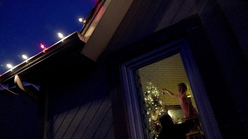 Molly Franz, 8, hangs ornaments on a Christmas tree while waiting for Thanksgiving dinner Thursday, Nov. 26, 2020, in Olathe, Kan. Franz lost her grandmother to COVID-19 on Nov. 10 and her family was having a quiet scaled-back Thanksgiving with just their household due to concerns about the virus. (AP Photo/Charlie Riedel)