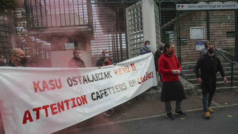 Restaurants and bars owners hold a banner that reads, 'attention angry coffee shop owners', as they stage a protest against the nation wide lockdown in front of a local administration center in Bayonne, southwestern France, Friday, Nov. 27, 2020. France's health minister said Thursday his country is readying to start administering COVID-19 vaccines in late December but warned that people will still have to wear masks and keep their distance even after vaccines are widely available. (AP Photo/Bob Edme)