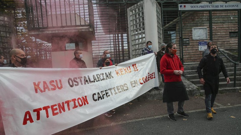 Restaurants and bars owners hold a banner that reads, 'attention angry coffee shop owners', as they stage a protest against the nation wide lockdown in front of a local administration center in Bayonne, southwestern France, Friday, Nov. 27, 2020. France's health minister said Thursday his country is readying to start administering COVID-19 vaccines in late December but warned that people will still have to wear masks and keep their distance even after vaccines are widely available. (AP Photo/Bob Edme)