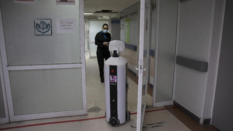 A healthcare worker communicates with a fellow doctor via Laluchy Robotina, a robot designed to aid in the mental health of patients infected with the new coronavirus, in the COVID-19 ward at 20 de November National Medical Center in Mexico City, Friday, Sept. 25, 2020. The 1.4-meter-tall robot that moves around on wheels visiting COVID-19 patients, is equipped with a camera and display screen which allows the patients to visit with relatives and to also communicate with healthcare workers, helping to reduce the risk of infection. (AP Photo/Marco Ugarte)