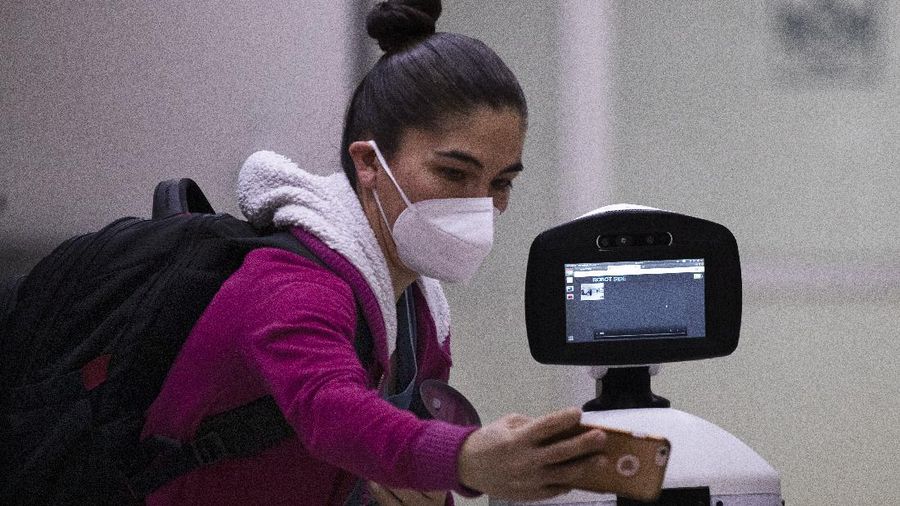 A healthcare worker communicates with a fellow doctor via Laluchy Robotina, a robot designed to aid in the mental health of patients infected with the new coronavirus, in the COVID-19 ward at 20 de November National Medical Center in Mexico City, Friday, Sept. 25, 2020. The 1.4-meter-tall robot that moves around on wheels visiting COVID-19 patients, is equipped with a camera and display screen which allows the patients to visit with relatives and to also communicate with healthcare workers, helping to reduce the risk of infection. (AP Photo/Marco Ugarte)