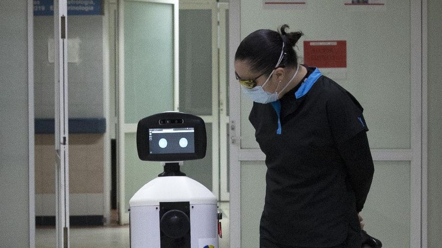 A healthcare worker communicates with a fellow doctor via Laluchy Robotina, a robot designed to aid in the mental health of patients infected with the new coronavirus, in the COVID-19 ward at 20 de November National Medical Center in Mexico City, Friday, Sept. 25, 2020. The 1.4-meter-tall robot that moves around on wheels visiting COVID-19 patients, is equipped with a camera and display screen which allows the patients to visit with relatives and to also communicate with healthcare workers, helping to reduce the risk of infection. (AP Photo/Marco Ugarte)