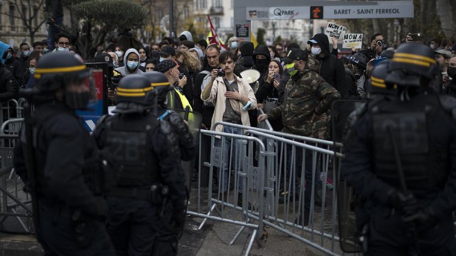 Protesters hold signs during a demonstration against a security law that would restrict sharing images of police, Saturday, Nov. 28, 2020 in Marseille. Civil liberties groups and journalists are concerned that the measure will stymie press freedoms and allow police brutality to go undiscovered and unpunished. The cause has gained fresh impetus in recent days after footage emerged of French police officers beating up a Black man, triggering a nationwide outcry. (AP Photo/Daniel Cole)