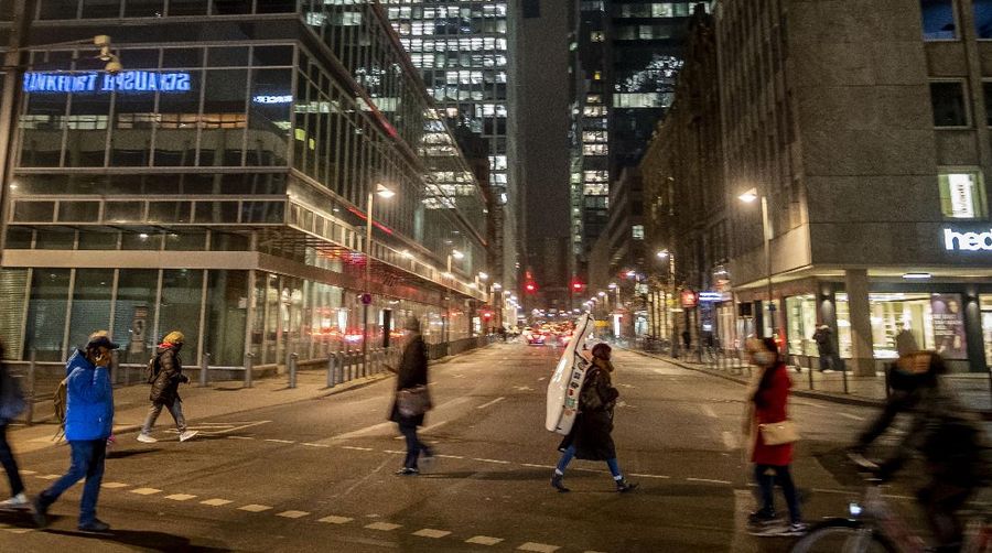 A woman carries a cello as she crosses a road in downtown Frankfurt, Germany, Thursday, Nov. 26, 2020. The German parliament discussed the new restrictions to avoid the outspread of the coronavirus today. (AP Photo/Michael Probst)
