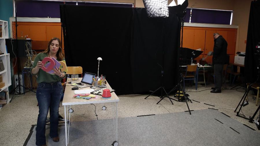 Teacher Rania Koukli prepares to record lessons that are broadcast on public television, at an elementary school in Athens, Wednesday, Nov. 18, 2020. Most other European countries have vowed to keep schools open, but the pandemic has hit Greece hard for the first time in recent weeks following a successful lockdown in the spring, overwhelming hospitals in parts of the country. State television is making and broadcasting lessons, while teachers sit in empty classrooms talking to remote students. Despite some problems, they say it keeps children in touch with their schools. (AP Photo/Thanassis Stavrakis)