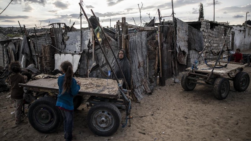 A Palestinian girl walks next to a donkey carte loaded with rocks in a slum on the outskirts of Khan Younis Refugee Camp, in the southern Gaza Strip, Wednesday, Nov. 25, 2020. Israel's blockade of the Hamas-ruled Gaza Strip has cost the seaside territory as much as $16.7 billion in economic losses and caused its poverty and unemployment rates to skyrocket, a U.N. report said Wednesday, as it called on Israel to lift the 13-year closure. (AP Photo/Khalil Hamra)