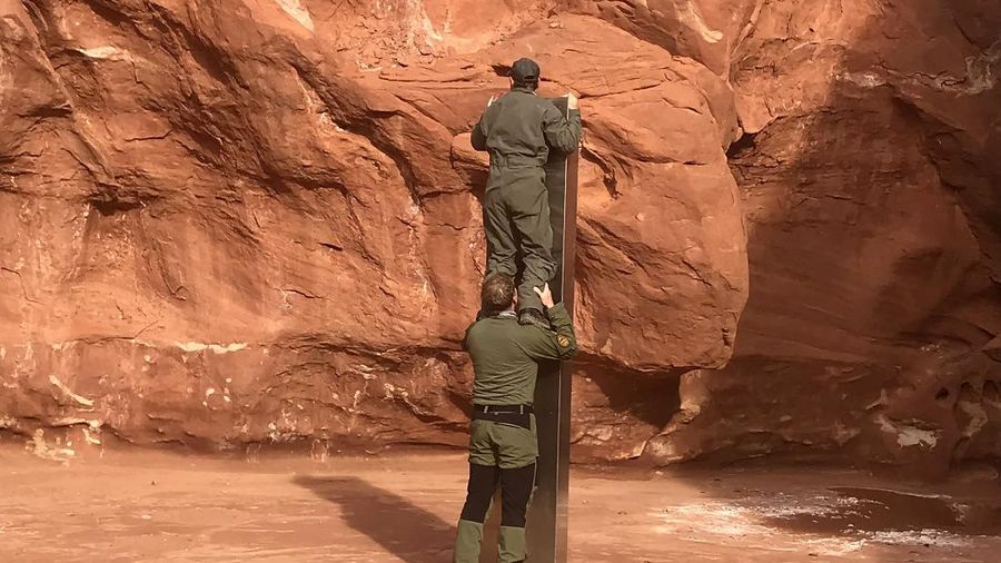 FILE - In this Nov. 18, 2020, file photo provided by the Utah Department of Public Safety, a Utah state worker stands next to a metal monolith in the ground in a remote area of red rock in Utah. The mysterious silver monolith that was placed in the Utah desert has disappeared less than 10 days after it was spotted by wildlife biologists performing a helicopter survey of bighorn sheep, federal officials and witnesses said. The Bureau of Land Management said it had received credible reports that the three-sided stainless steel structure was removed on Nov. 27.  (Utah Department of Public Safety via AP, File)