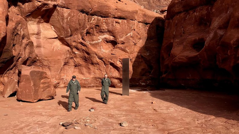 FILE - In this Nov. 18, 2020, file photo provided by the Utah Department of Public Safety, a Utah state worker stands next to a metal monolith in the ground in a remote area of red rock in Utah. The mysterious silver monolith that was placed in the Utah desert has disappeared less than 10 days after it was spotted by wildlife biologists performing a helicopter survey of bighorn sheep, federal officials and witnesses said. The Bureau of Land Management said it had received credible reports that the three-sided stainless steel structure was removed on Nov. 27.  (Utah Department of Public Safety via AP, File)