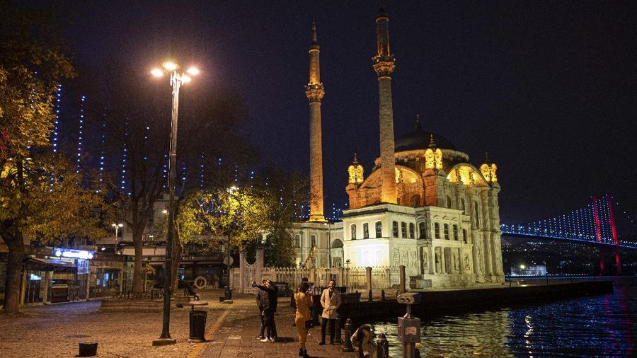 People walk in Istanbul, backdropped by the Galata Tower, during a curfew Tuesday, Dec. 1, 2020, part of the new measures to try curb the spread of the coronavirus. Turkey had gone into the most widespread lockdown so far amid a surge in COVID-19 infections, extending curfews to weeknights and full lockdowns over weekends. The curfew would be implemented on weekdays between 9:00 pm and 5:00 am. He also announced total weekend lockdowns from 9:00 pm on Friday evenings to 5:00 am Monday. (AP Photo)