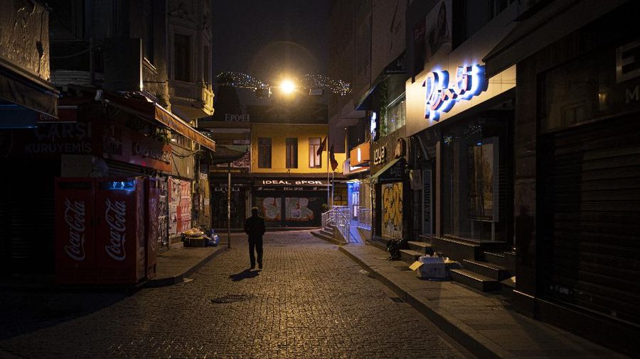 People walk in Istanbul, backdropped by the Galata Tower, during a curfew Tuesday, Dec. 1, 2020, part of the new measures to try curb the spread of the coronavirus. Turkey had gone into the most widespread lockdown so far amid a surge in COVID-19 infections, extending curfews to weeknights and full lockdowns over weekends. The curfew would be implemented on weekdays between 9:00 pm and 5:00 am. He also announced total weekend lockdowns from 9:00 pm on Friday evenings to 5:00 am Monday. (AP Photo)