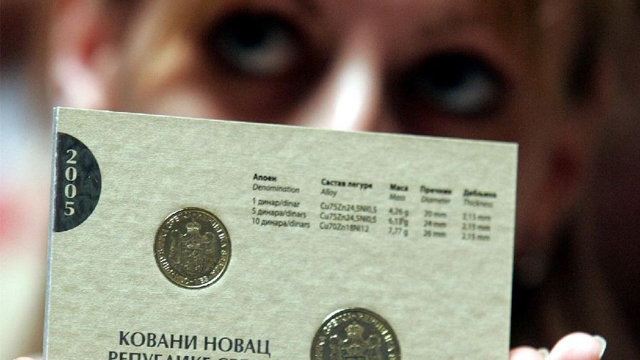 A National Bank employee displaying new coins of the national currency dinar, with a traditional Serbian coat of arms which was abolished during decades of Communist rule, in Belgrade, Friday, July 1, 2005. Serbia is part of Serbia-Montenegro union but the two republics use different currencies and have separate monetary system. (AP Photo/Darko Vojinovic)