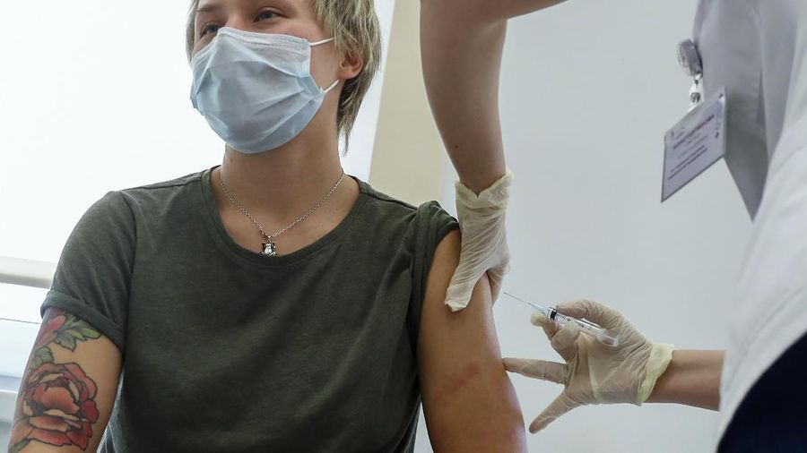 Russian medical worker, right, administers a shot of Russia's Sputnik V coronavirus vaccine in Moscow, Russia, Saturday, Dec. 5, 2020. Thousands of doctors, teachers and others in high-risk groups have signed up for COVID-19 vaccinations in Moscow starting Saturday, a precursor to a sweeping Russia-wide immunization effort. (AP Photo/Pavel Golovkin)