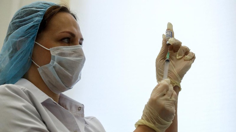 Russian medical worker, right, administers a shot of Russia's Sputnik V coronavirus vaccine in Moscow, Russia, Saturday, Dec. 5, 2020. Thousands of doctors, teachers and others in high-risk groups have signed up for COVID-19 vaccinations in Moscow starting Saturday, a precursor to a sweeping Russia-wide immunization effort. (AP Photo/Pavel Golovkin)