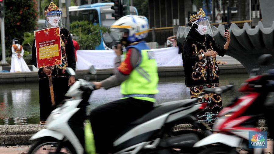 Aksi warga mengenakan pakaian adat menyerukan ajakan patuhi aturan Covid-19 saat Pilkada berlangsung disejumlah daerah di Kawasan Patung Kuda Monas, Jakarta, Senin 7/12. (CNBC Indonesia/Muhammad Sabki)